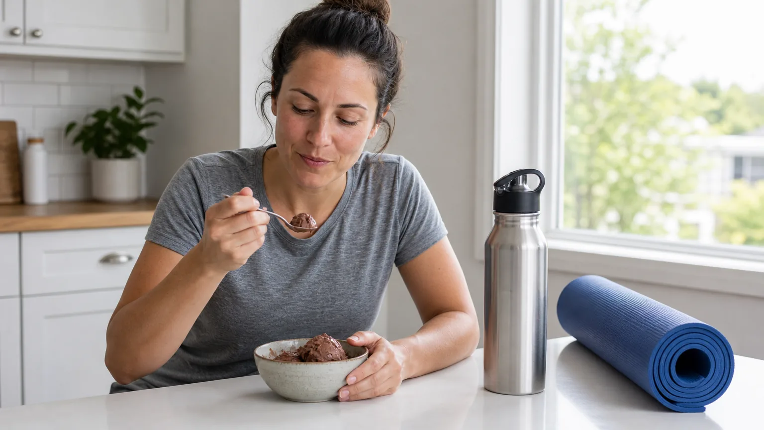 Woman eating chocolate ice cream beside a yoga mat