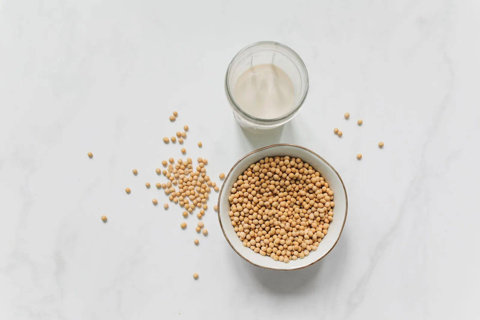 Bowl of soybeans beside a glass of soy milk