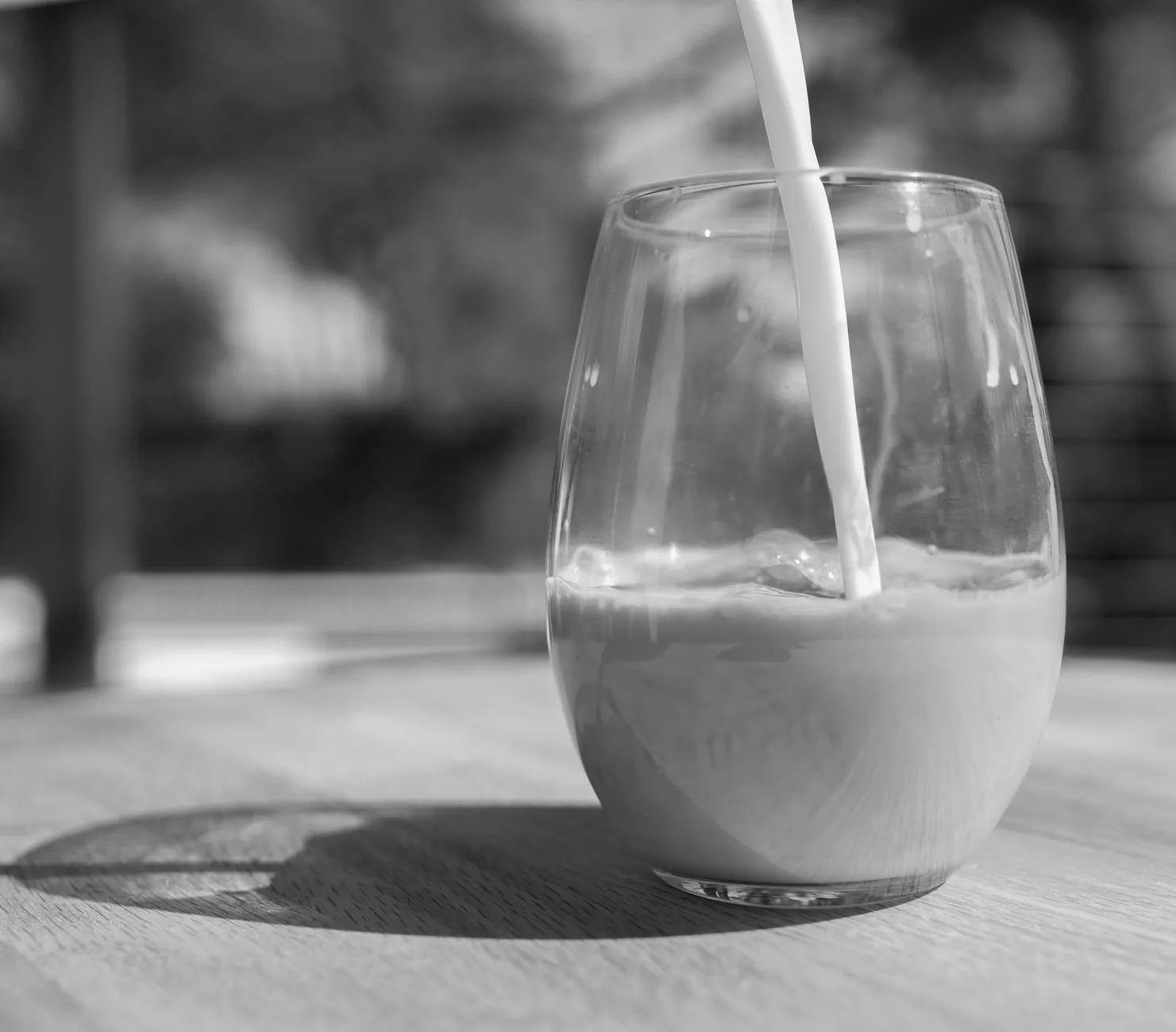Milk pouring into a glass on a wooden table