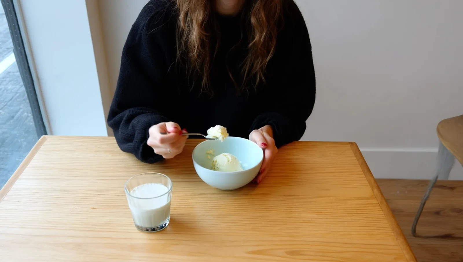 A person eating a bowl of ice cream at a kitchen table