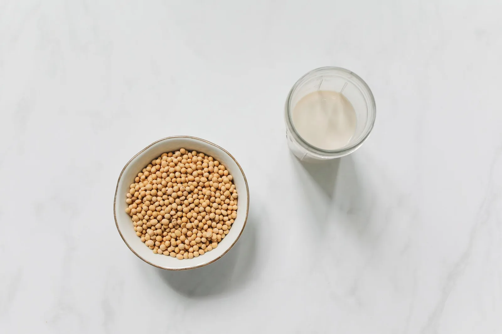 Bowl of soybeans beside a glass of soy milk