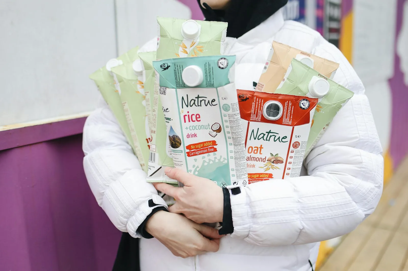 Shopper holding an assortment of plant-based milk cartons used as bases for non-dairy ice cream.